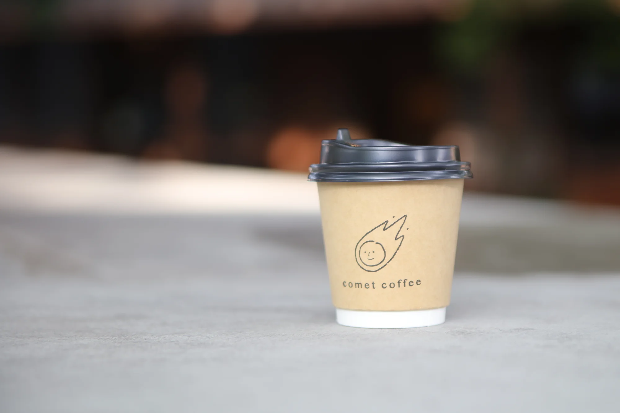 蔵を背に置かれた Comet Coffee のロゴ入りカップ