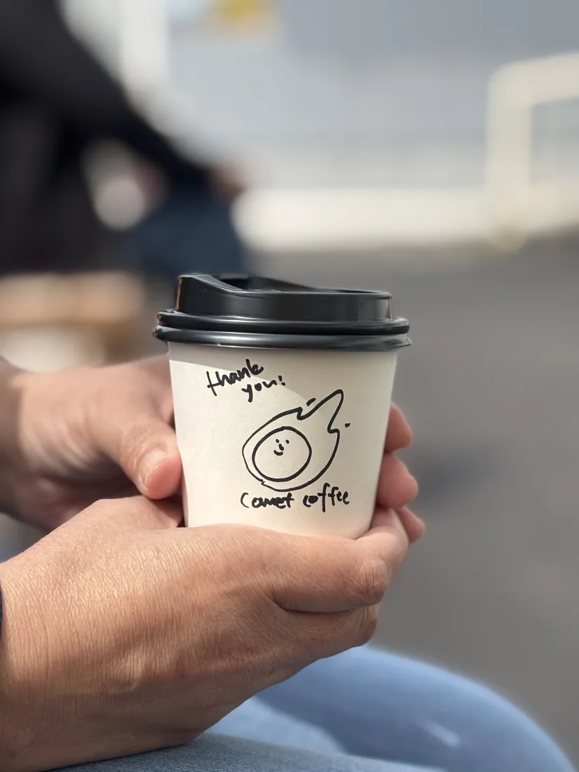 「thank you」と書き添えたテイクアウトカップを両手で受け取るところ